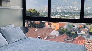 Een slaapkamer met een groot raam en uitzicht over de stad.
