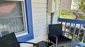 En veranda med två stolar och ett litet bord, en mönstrad matta och ett räcke.