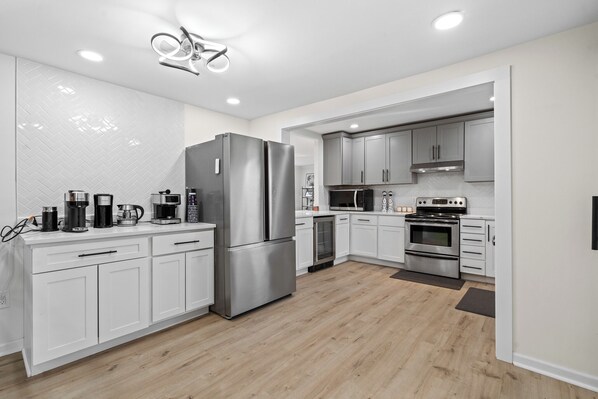 A modern kitchen with white cabinetry, stainless steel appliances, and a herringbone tile backsplash.