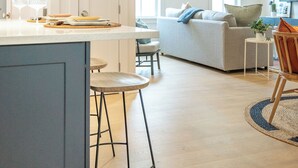 A modern kitchen with a central island, bar stools, and pendant lighting.