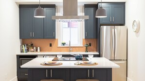 A modern kitchen with dark cabinets, stainless steel appliances, and a central island with stools.