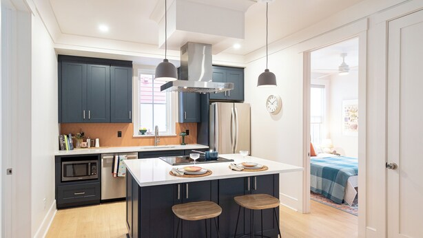 A modern kitchen with dark cabinets, a central island with stools, and a large stove.