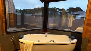 A wooden cabin with a large window, a bathtub, and a wooden floor. - Chalé Cabernet - Vila Chamonix (Urubici)