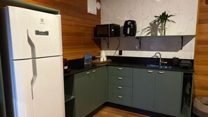 A compact kitchen with a white refrigerator, dark green cabinets, a wooden ceiling, and a marble backsplash. - Chalé Cabernet - Vila Chamonix (Urubici)