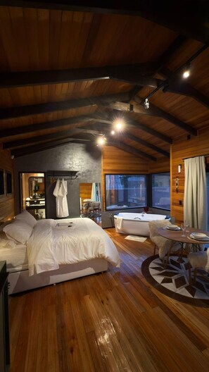 Ein gemütliches Schlafzimmer mit einem großen Bett, einem kleinen Tisch und einer Badewanne.