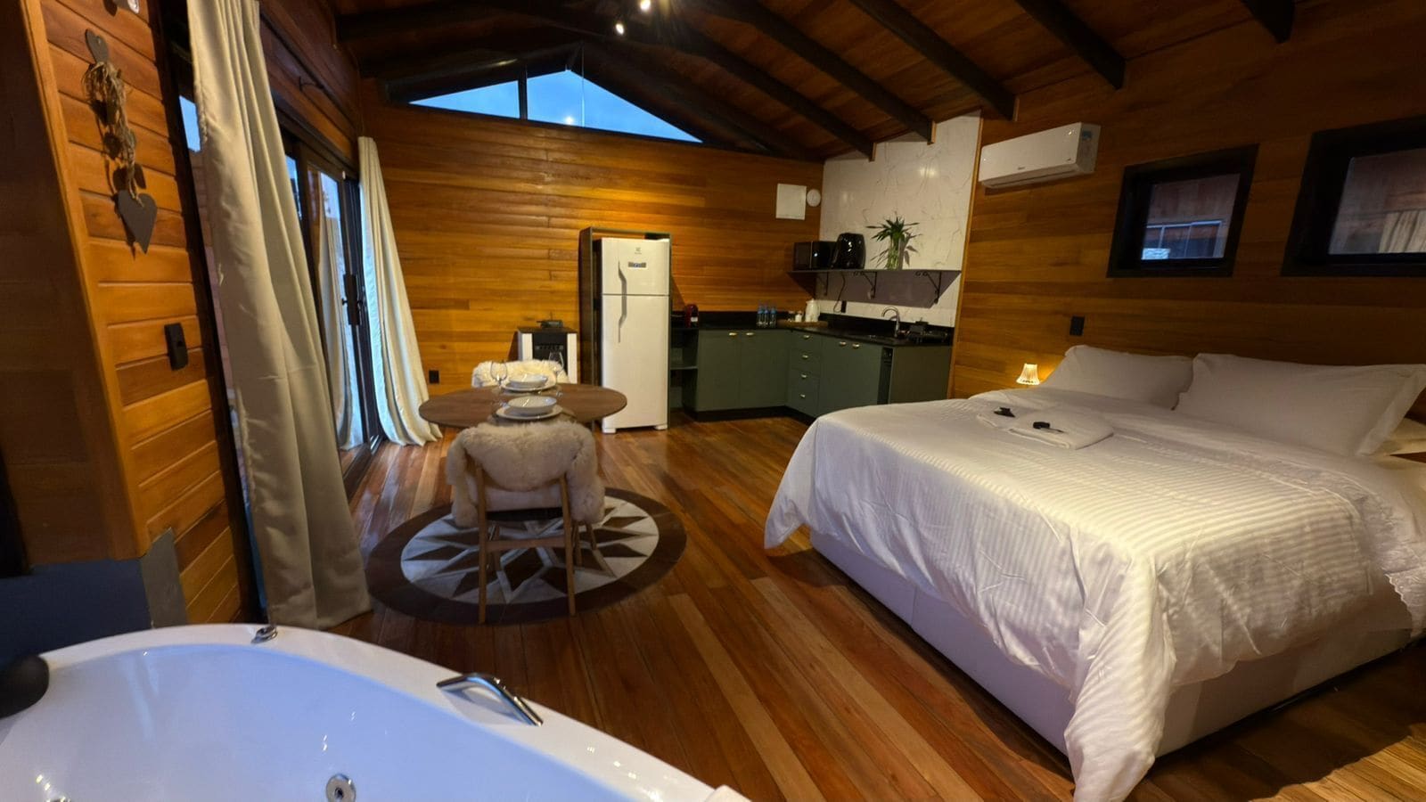 Una habitación acogedora con una cama grande, una mesa de comedor, una zona de cocina y una bañera.