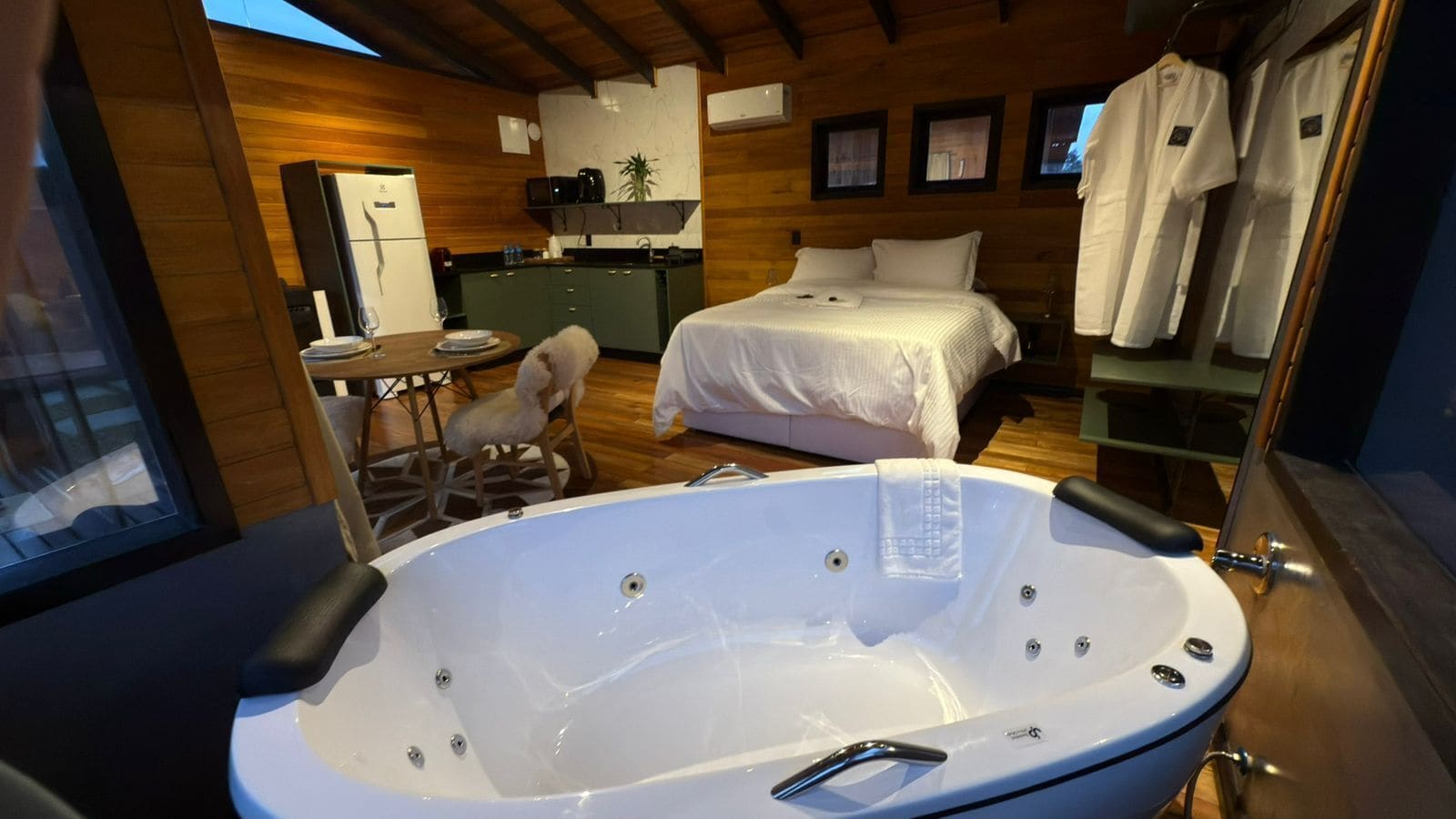 Une pièce comprenant une grande baignoire, un lit, un petit coin cuisine et une table à manger.