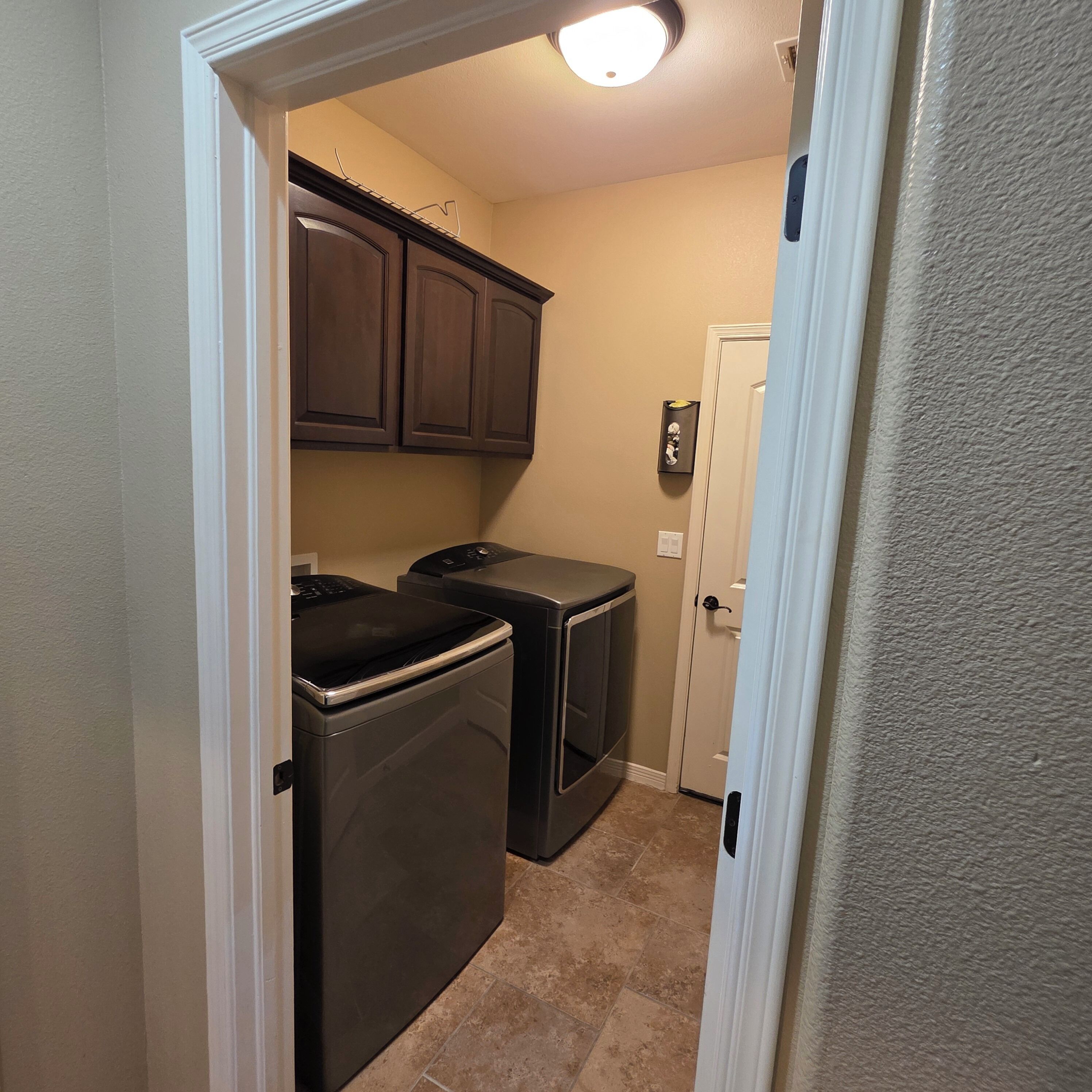 A compact kitchen with dark wooden cabinets, a washing machine, and a dryer.
