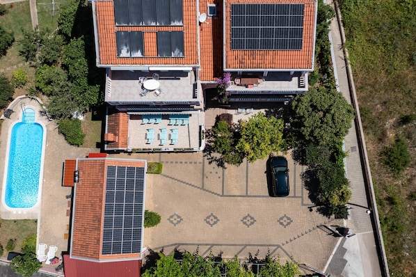 A residential property with a swimming pool, solar panels, and a patio area.