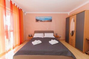 A bedroom with a bed, two pillows, a nightstand, a wardrobe, and a painting on the wall.