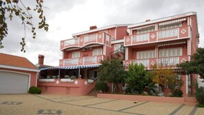 A multi-story building with balconies, a covered entrance, and a paved courtyard.
