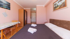 A bedroom with a bed, a table with chairs, and a painting on the wall.