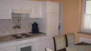 Une cuisine avec des meubles blancs, une cuisinière et une table à manger avec des chaises.