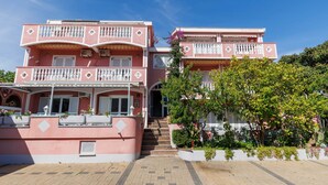 Un bâtiment rose doté de balcons, d’un escalier et de plantes en pot.