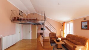 Un vaste salon doté d’un plancher en bois, d’un canapé en cuir marron, d’une table basse en bois et d’un escalier menant à l’étage supérieur.