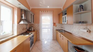 Une cuisine moderne avec des meubles en bois, un évier en acier inoxydable et une fenêtre avec un rideau.