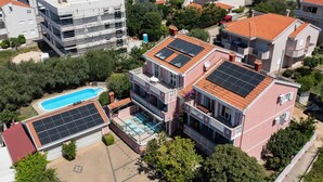 A residential building with solar panels, a swimming pool, and a covered outdoor area.