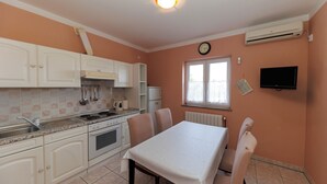 A kitchen with white cabinets, a stove, and a dining table with chairs.
