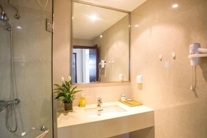 Een badkamer met een glazen douchecabine, een wastafel met spiegel en een handdoekrek.