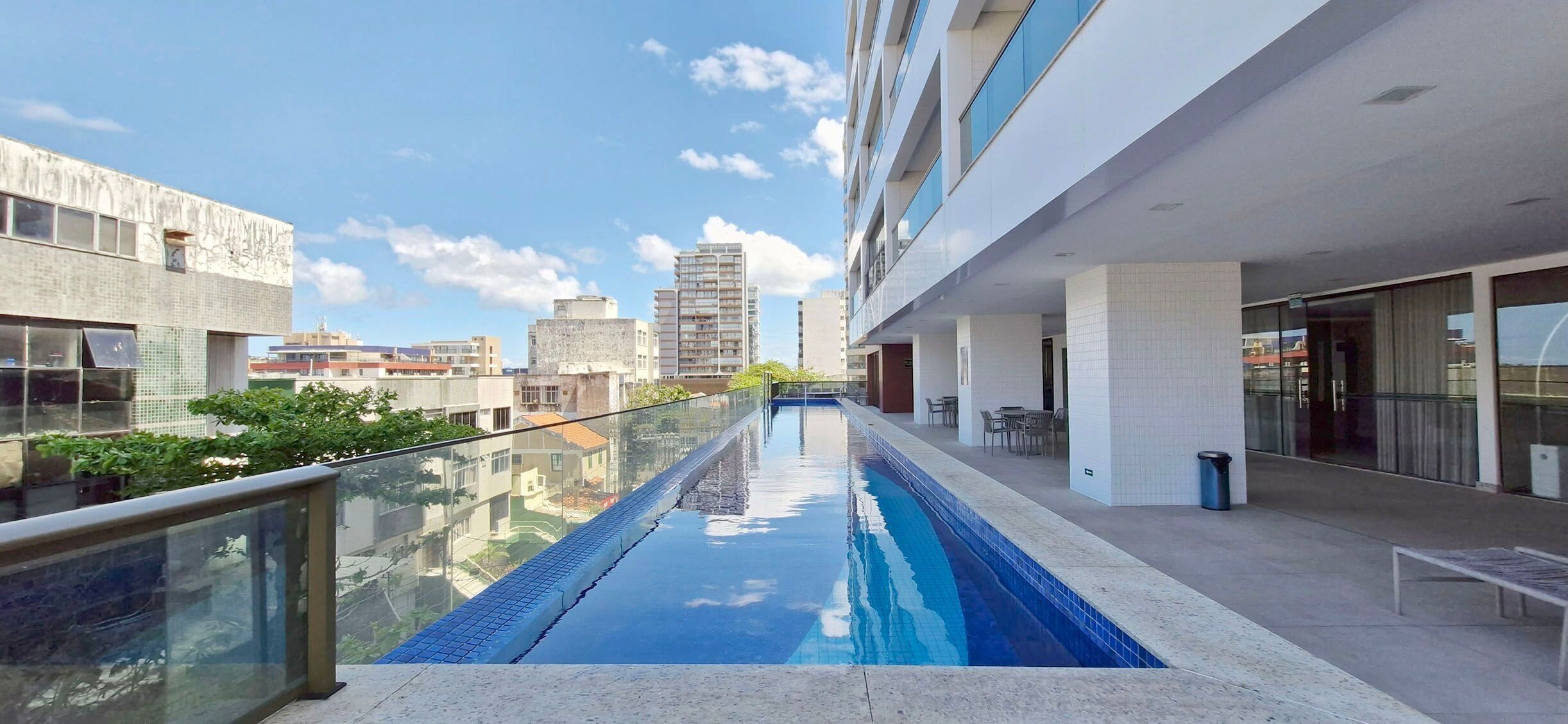 Un edificio moderno con una piscina larga y estrecha en el centro, rodeada de barandillas de vidrio.