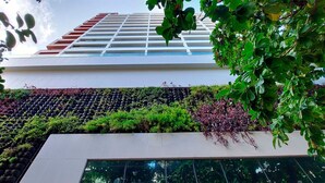 A modern building with a glass facade and a rooftop garden with various plants.