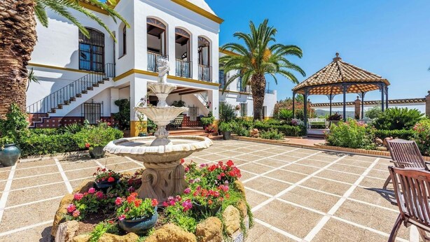 A courtyard with a fountain, palm trees, and a gazebo. - Cortijo Hacienda Nueva Lora del Río by Ruralidays (Sevilla)