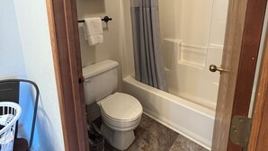 A bathroom with a toilet, a bathtub, and a shower curtain. - Red Bell Inn (Leavenworth)