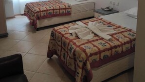 A hotel room with two beds, a window with curtains, a bedside table with a phone, and a tiled floor. - DEFNE OTEL  (Polatli)