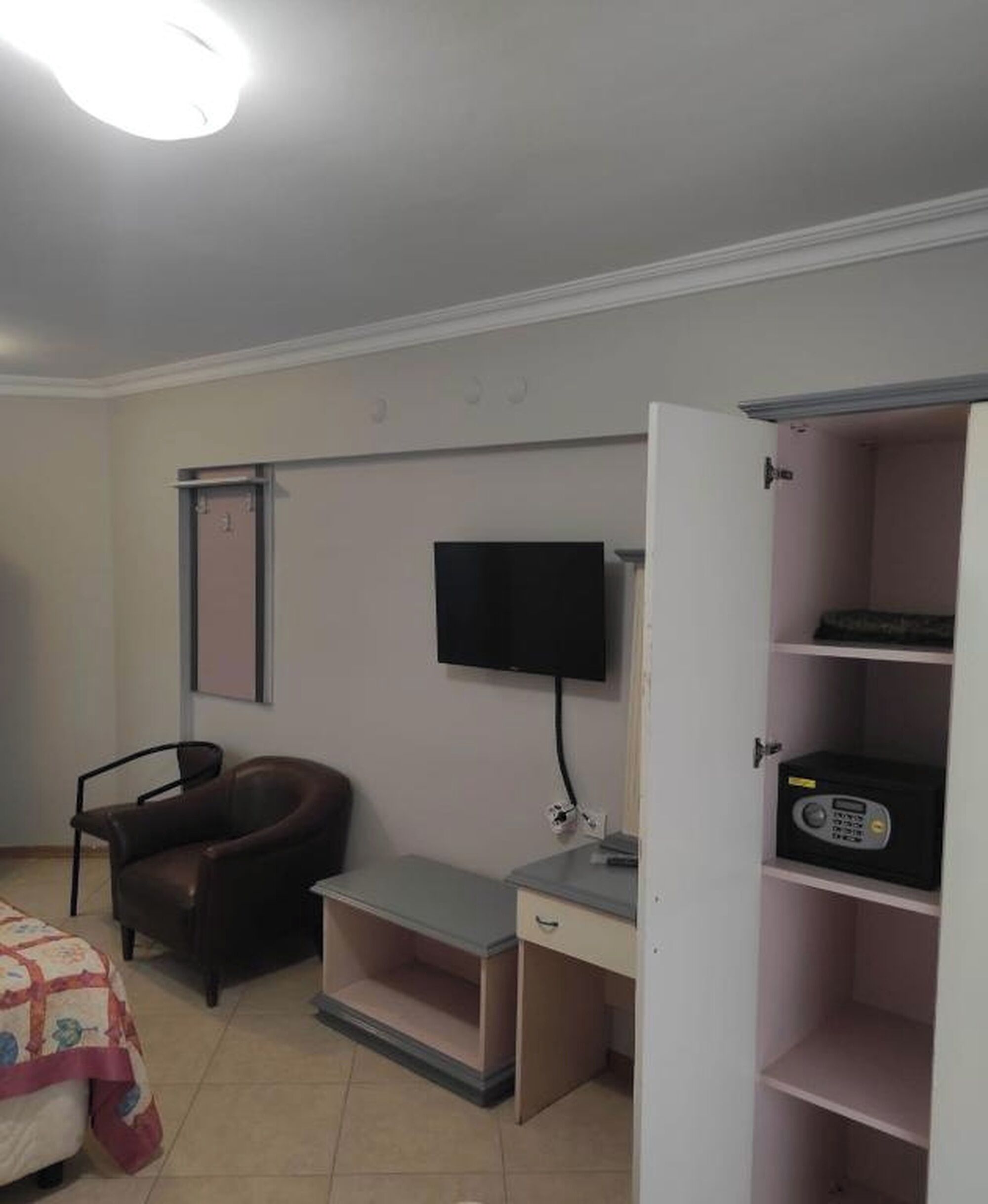 A bedroom with a bed, a desk, a chair, a television, and a wardrobe.