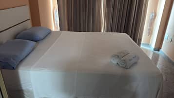 A hotel room with a neatly made bed, a headboard, and a pair of towels on the bed.