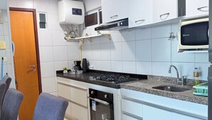 A modern kitchen with white cabinets, a built-in oven, a microwave, and a sink. - Terraços do Atlântico - 2 (Fortaleza)