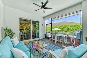 A spacious living area with a ceiling fan, a sofa, a coffee table, and a view of a patio with outdoor furniture. - 131 Seminole Ln (Cocoa Beach)