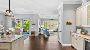 A spacious living area with a kitchen, dining area, and a view of greenery outside. - 131 Seminole Ln (Cocoa Beach)
