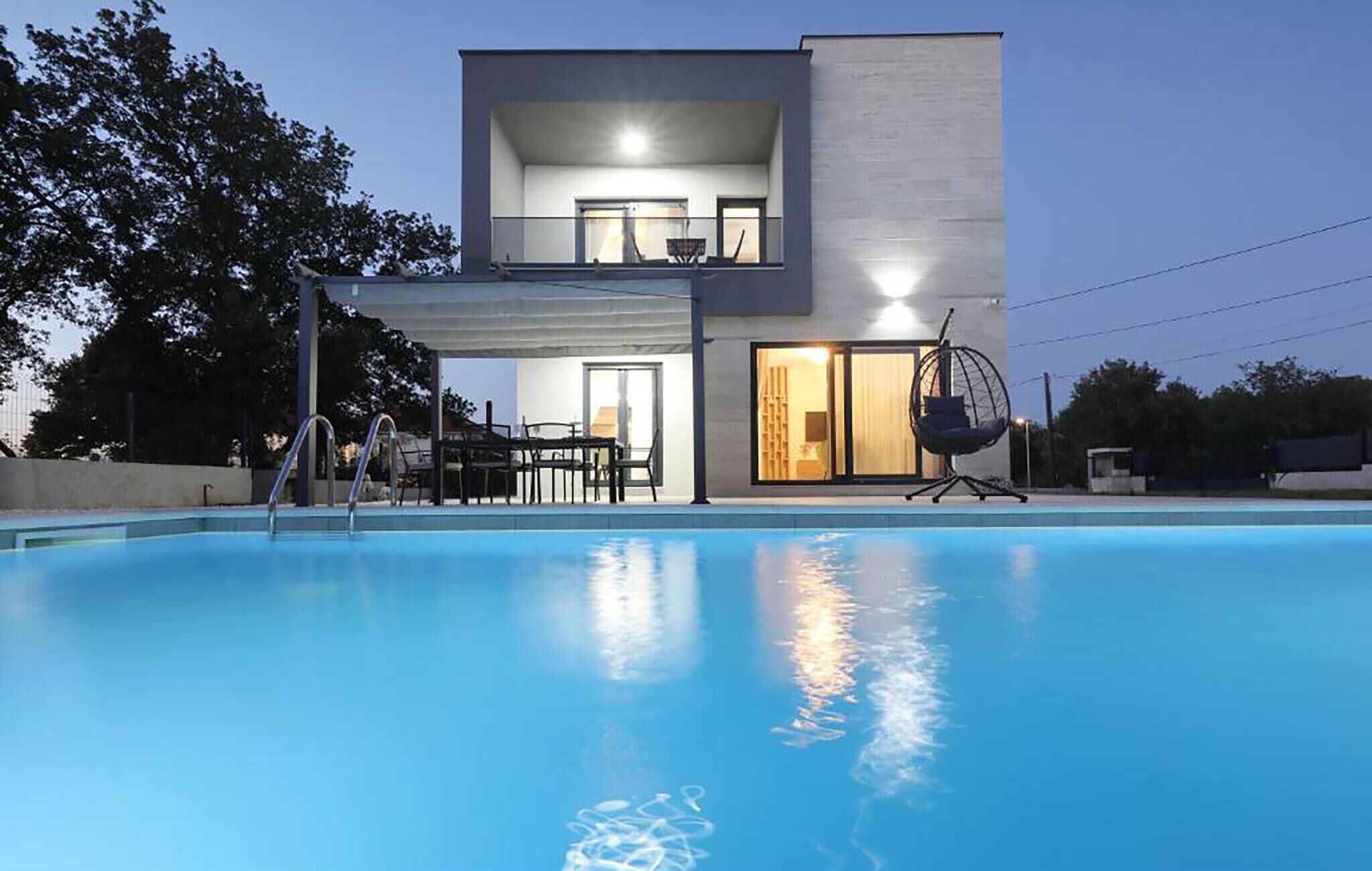 A modern two-story building with a swimming pool in the foreground.