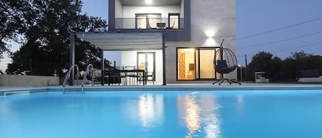 A modern two-story building with a swimming pool in the foreground.