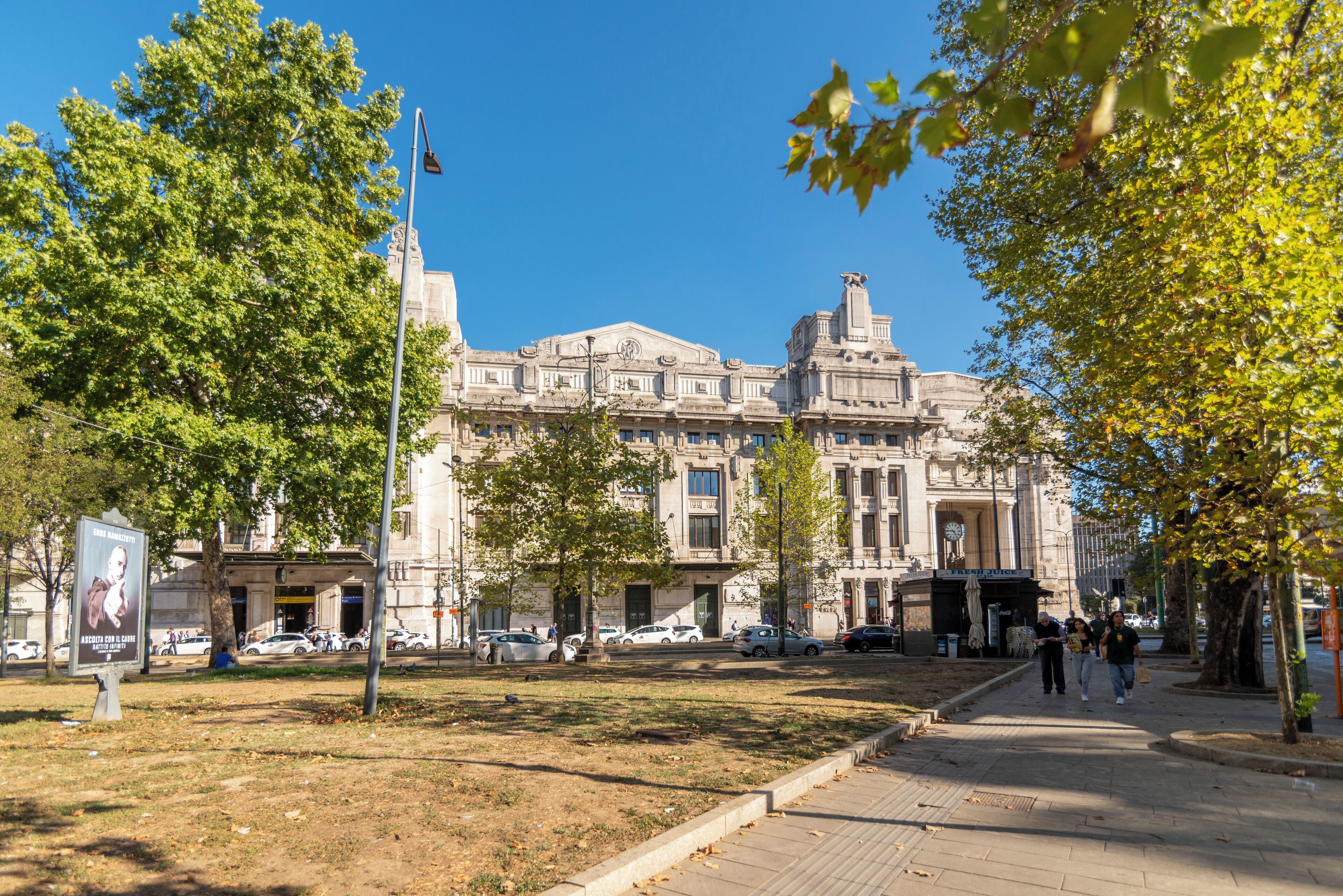 A historic building with classical architecture, a paved walkway, and trees.