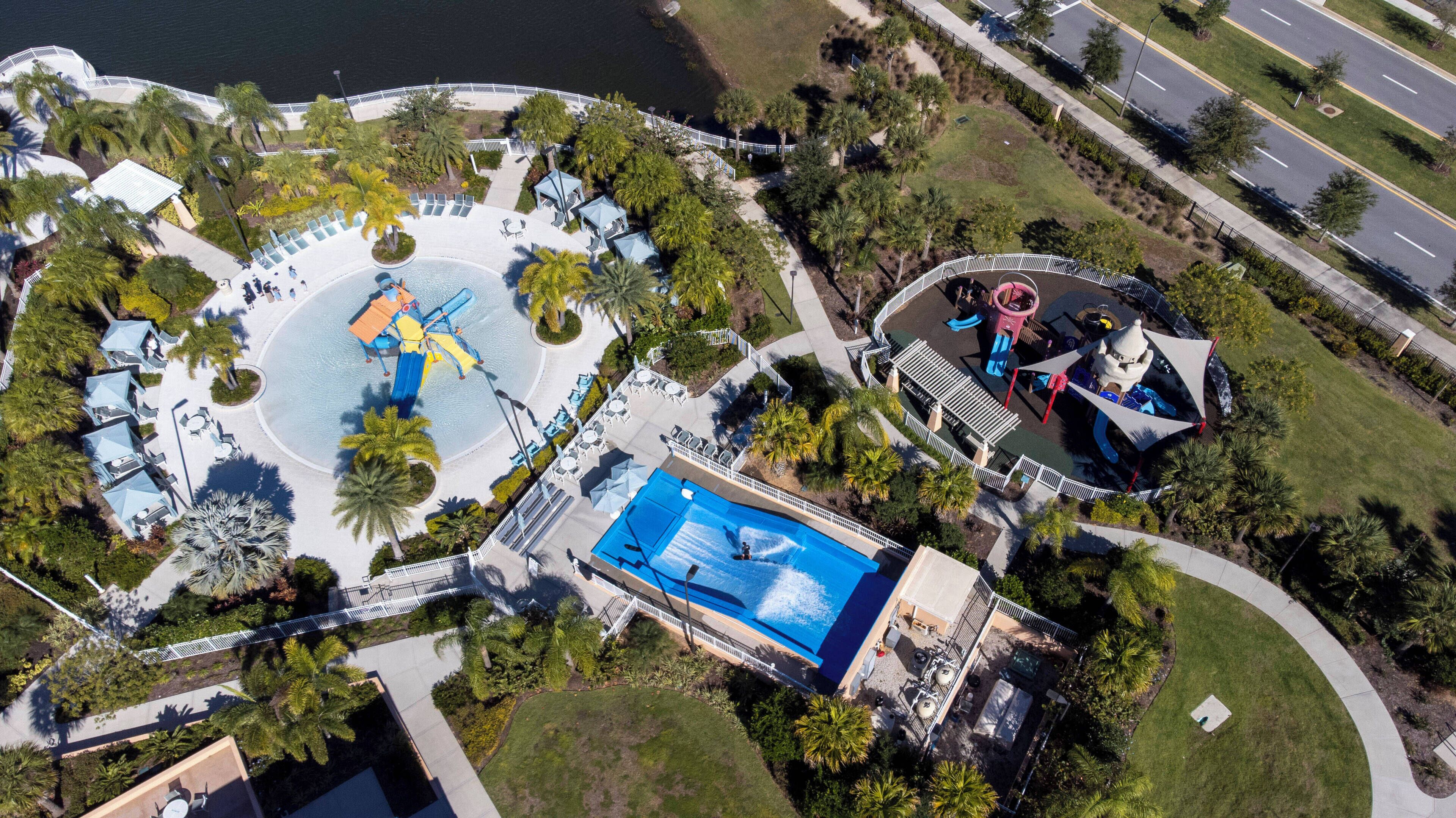 An aerial view of a resort with a large pool, water slides, and a play area.