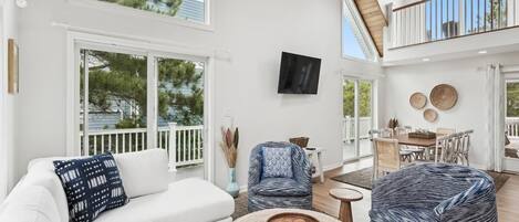 A spacious living area with a white sofa, blue patterned armchair, and a round woven coffee table.