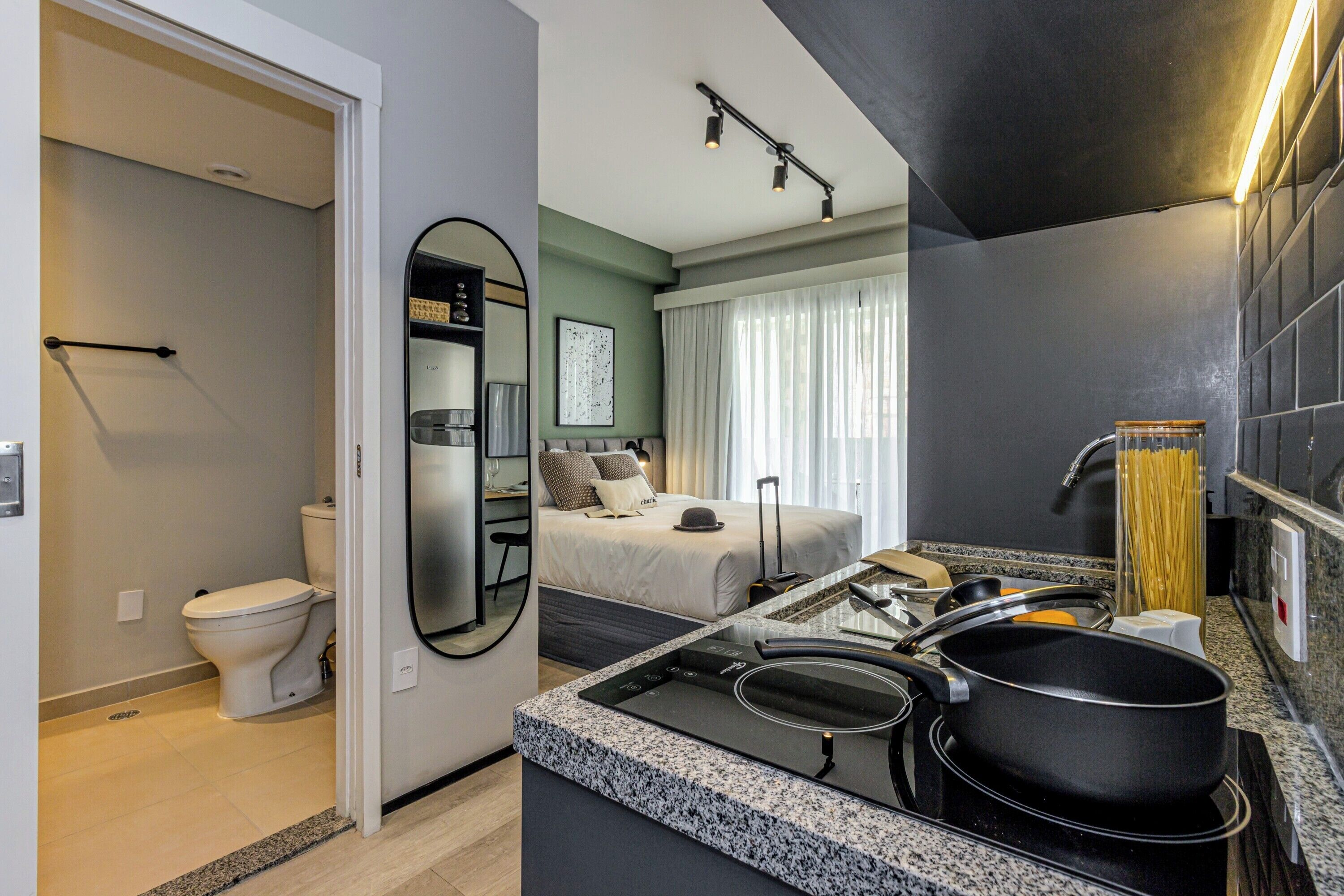 Een moderne hotelkamer met een kitchenette, een badkamer en een groot bed.