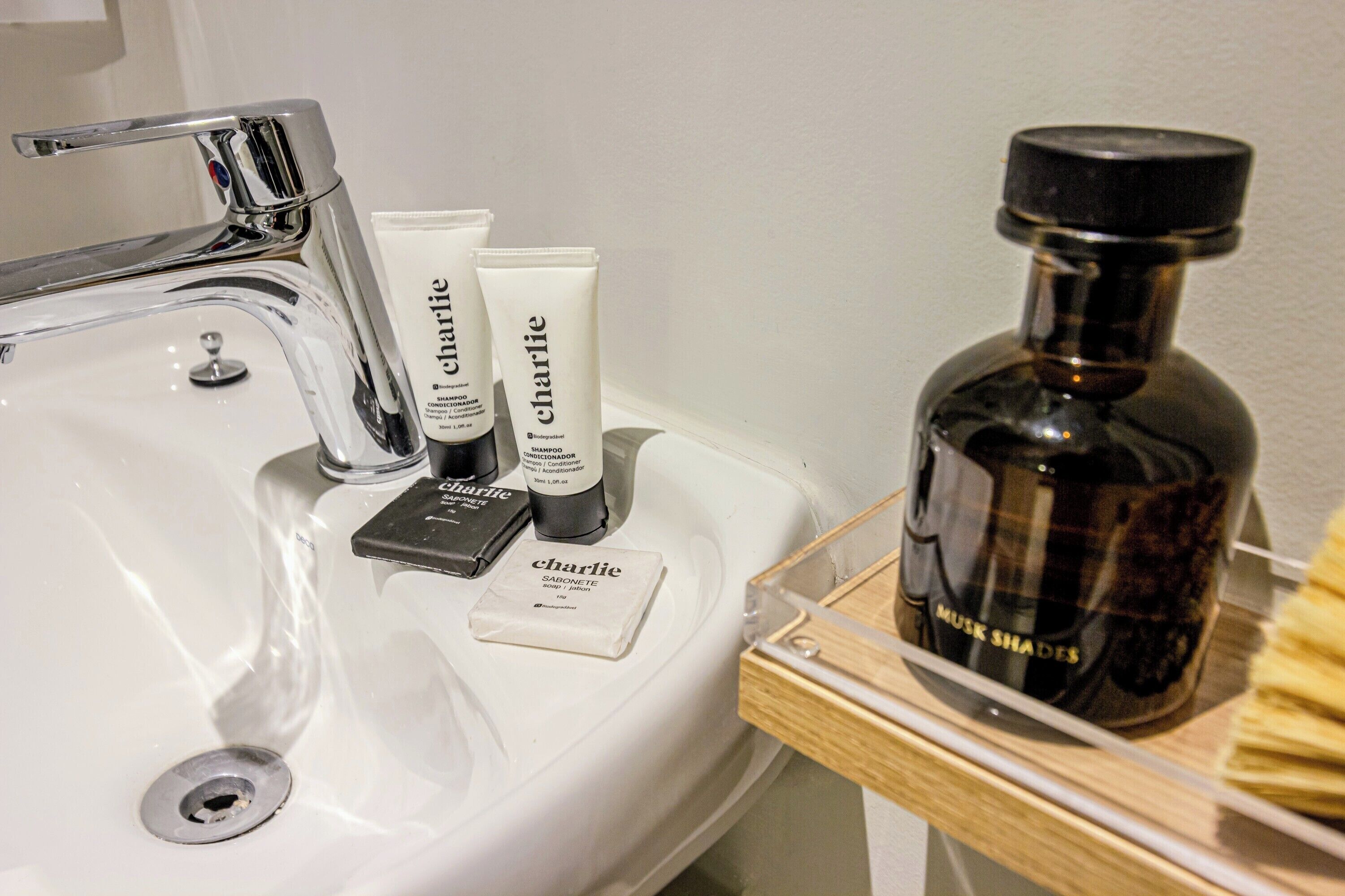 A bathroom sink with toiletries including a bottle of shampoo, a tube of soap, and a bar of soap.