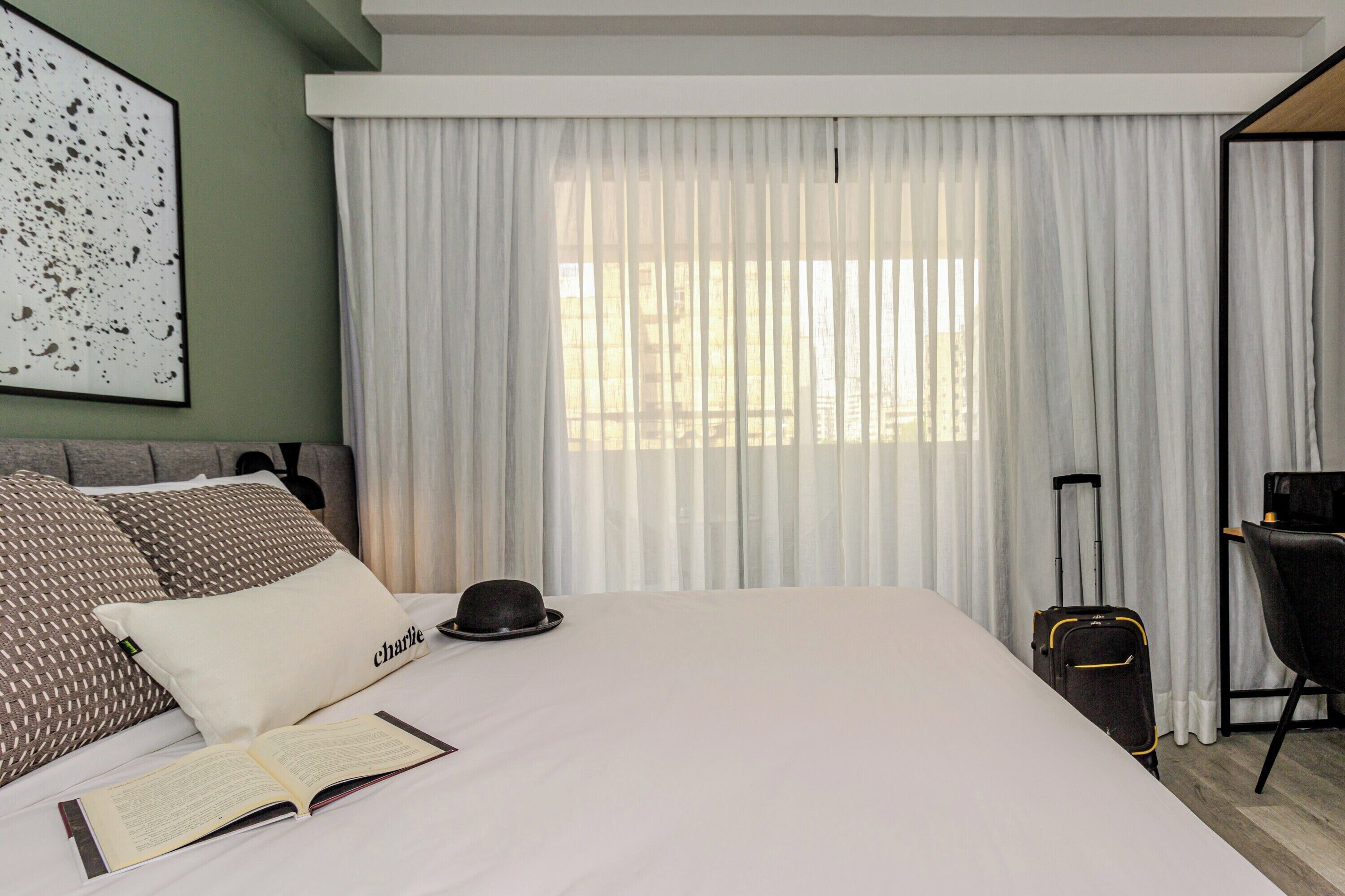 A hotel room with a large bed, a desk, and a suitcase.