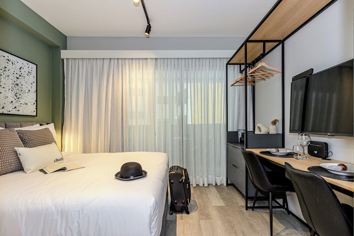 Une chambre d’hôtel comprenant un lit, un bureau, une chaise, une télévision et une armoire.