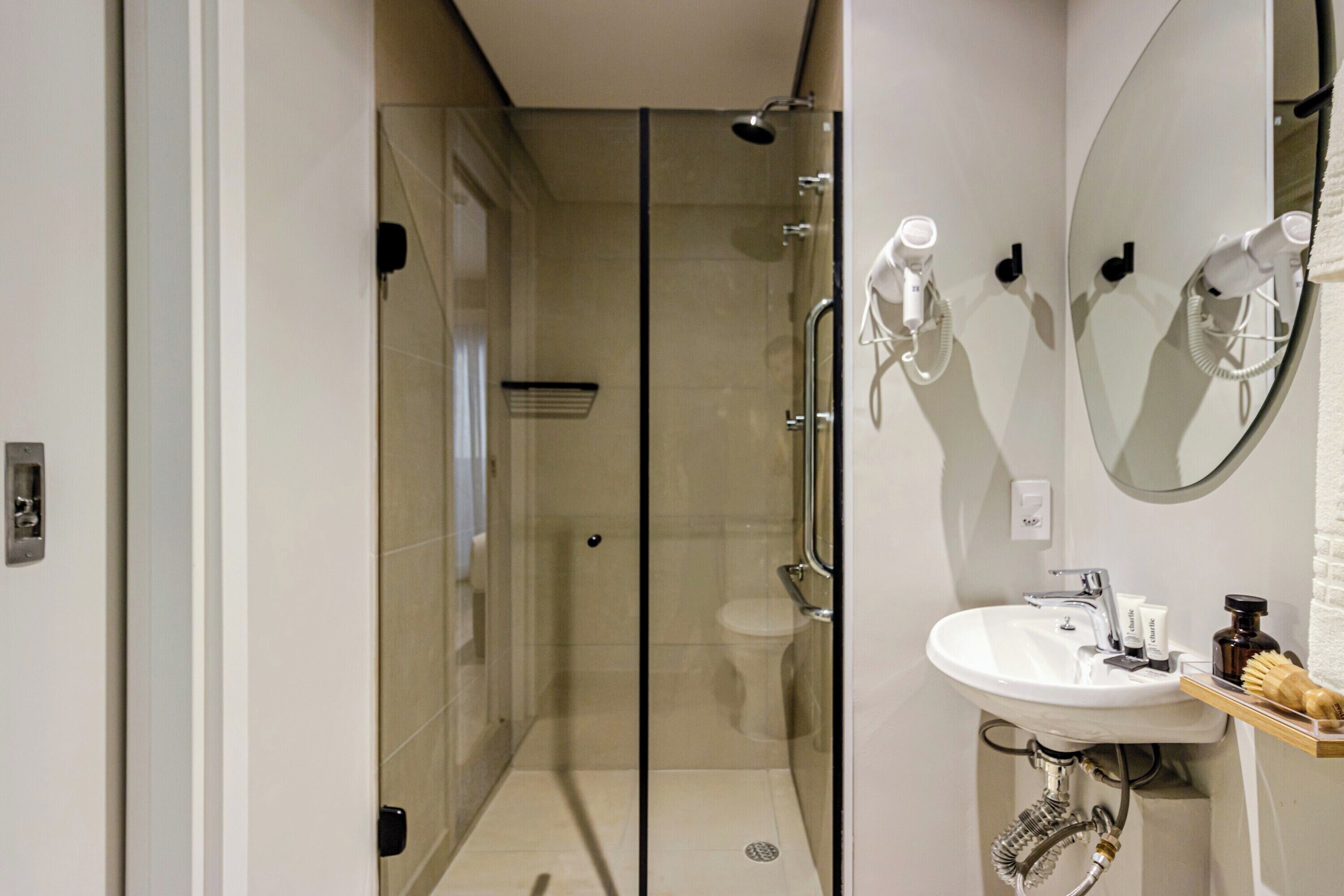 A modern bathroom with a glass-enclosed shower, a white sink with a mirror above it, and a towel rack.