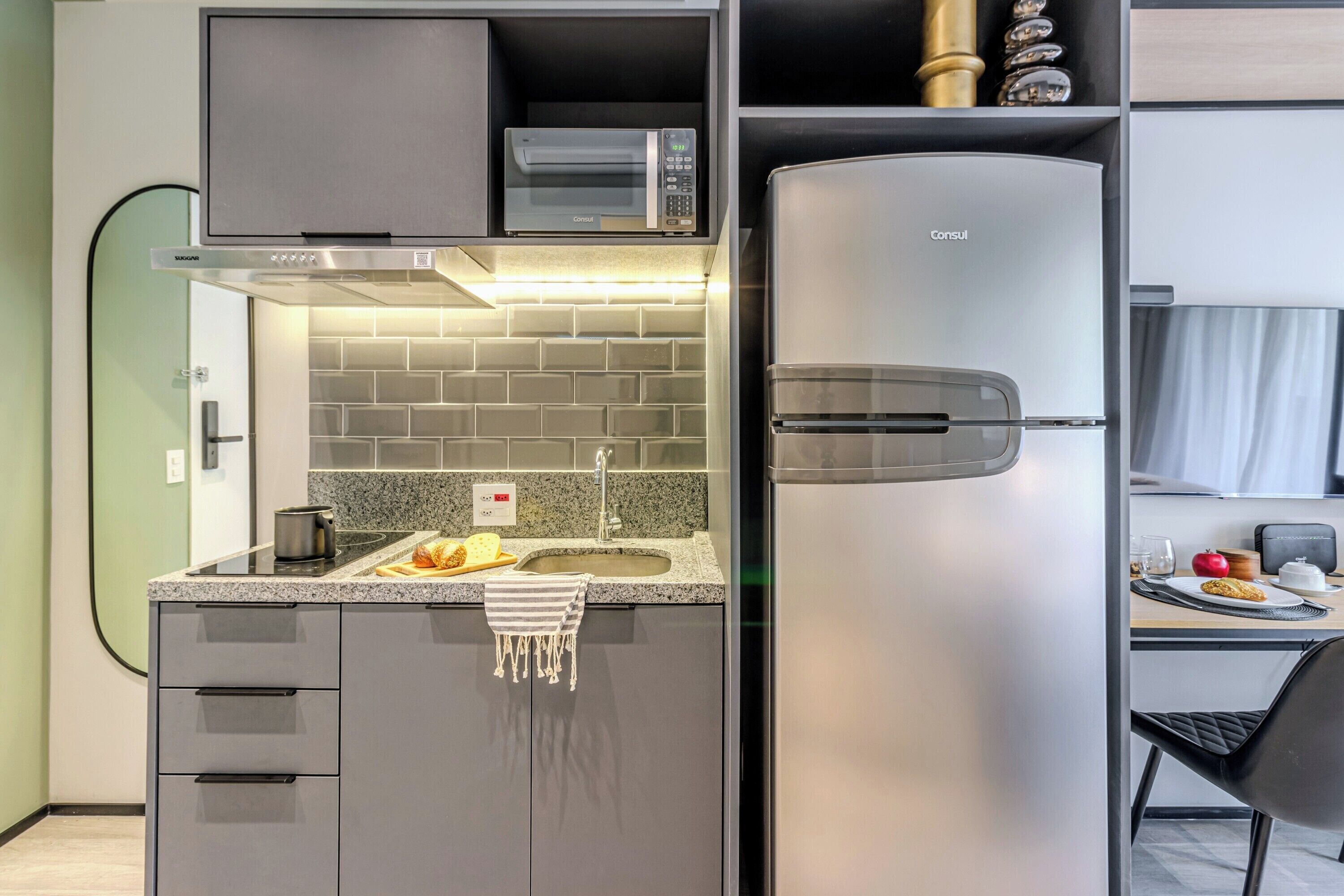 Eine moderne Küche mit eingebauter Mikrowelle, einem Edelstahlkühlschrank und einer Arbeitsplatte aus Granit.