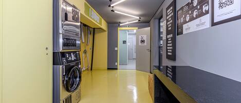 A hallway with a yellow floor, a washing machine, and a black counter with a QR code.