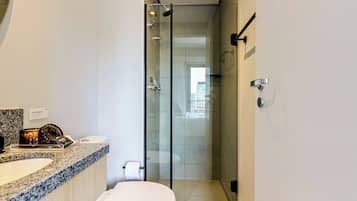 A modern bathroom with a granite countertop, a toilet, and a glass-enclosed shower.