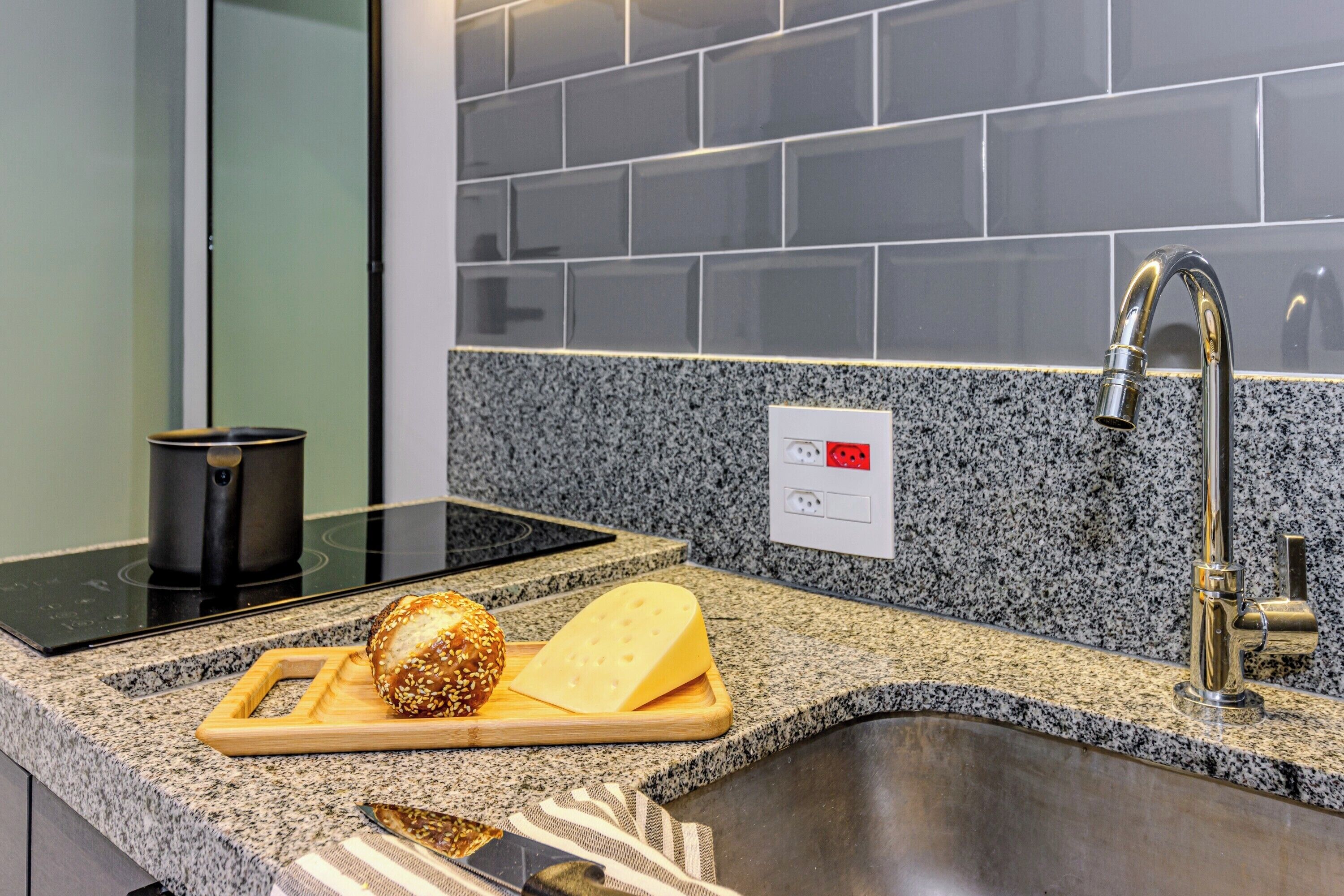 A kitchen with granite countertops, a stainless steel sink, a built-in oven, and a modern faucet.