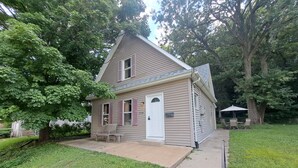 A two-story house with a front porch, a mailbox, and a patio area with outdoor furniture. - Whole Home by Heritage Trail, quiet street, outdoor games (Dubuque)