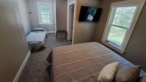 A bedroom with a large bed, a TV mounted on the wall, and a window providing a view of the outdoors. - Whole Home by Heritage Trail, quiet street, outdoor games (Dubuque)