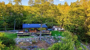Une cabane moderne dotée d’une terrasse, entourée d’une forêt dense.